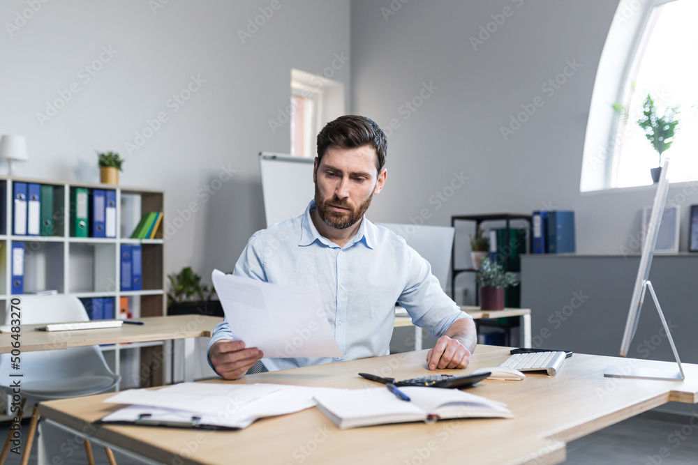 Thinking businessman working with documents in the office, man reviewing financial reports - obrazy, fototapety, plakaty 