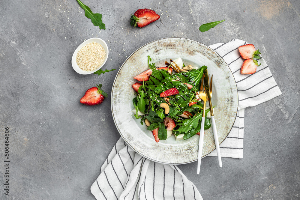 Fresh vegetarian salad with strawberry, spinach leaves and feta cheese on gray stone background, banner, menu, recipe place for text, top view