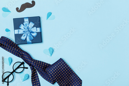Father's day dad concept. Gift tie glasses mustache big hearts on a blue background.