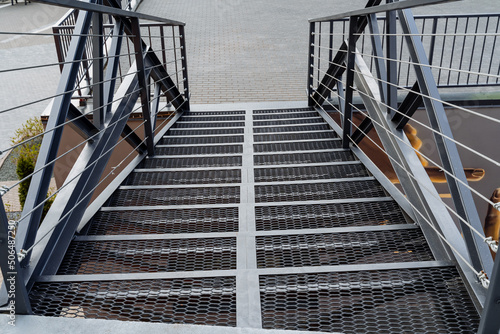 Iron staircase transition between floors. pedestrian ladder above the road, railings made of profile, metal cables stretched between the beams.