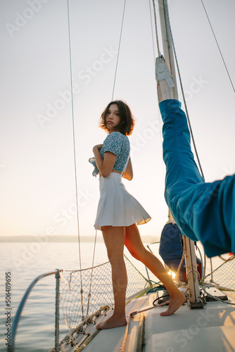 Calm young lady admiring nature while standing on sailboat photo