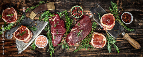 Raw beef filet Mignon steak on with pepper and salt, filet mignon. beef tenderloin steaks wrapped in bacon and thyme on dark background. Long banner format. top view