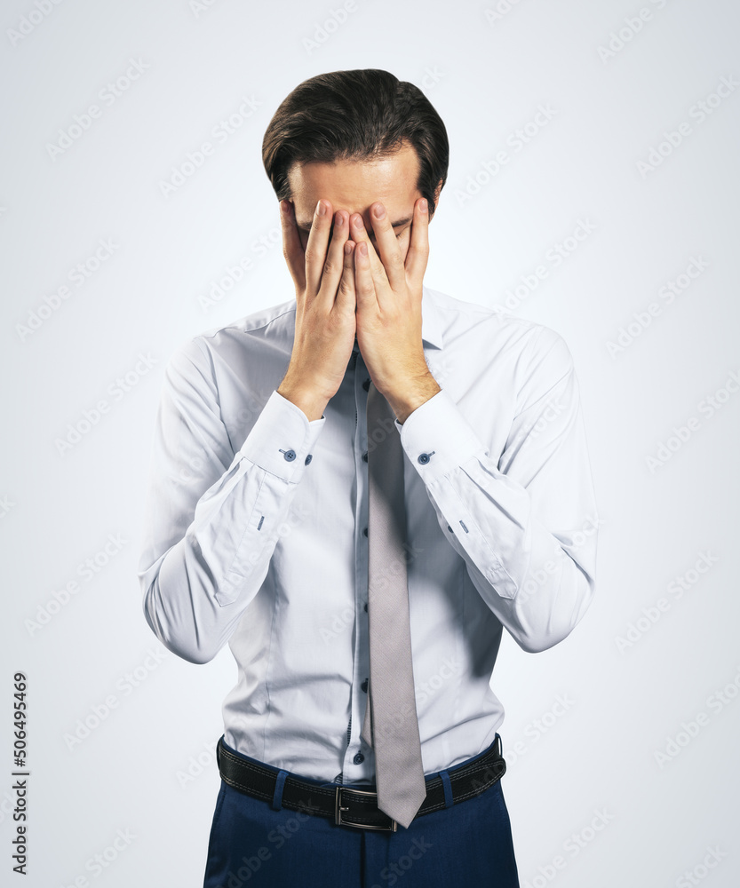 Stress and find solution concept with man in white shirt closing his eyes, facepalm isolated on light grey background Stress and find solution concept with man in white shirt closing his eyes, facepalm isolated on light grey background