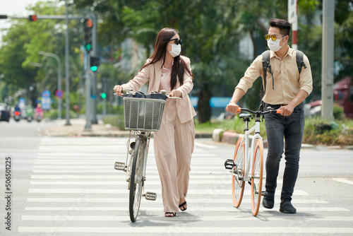 Business people wearing sunglasses and medical masks crossing road on pedestrian crossing photo