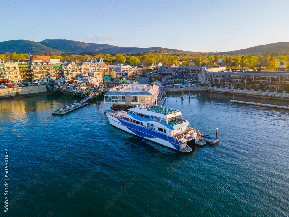 Fototapeta premium Whale watch ship aerial view docked at pier at sunset in historic town center of Bar Harbor on Mt Desert Island, Maine ME, USA. 