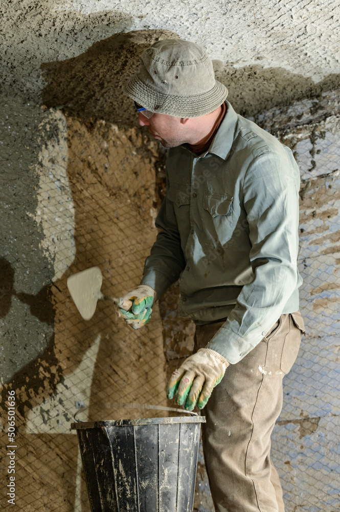 A man throws concrete mortar on the wall, the first layer of plaster on the wall, repair work in Ukraine. A man throws concrete mortar on the wall, the first layer of plaster on the wall, repair work in Ukraine.
