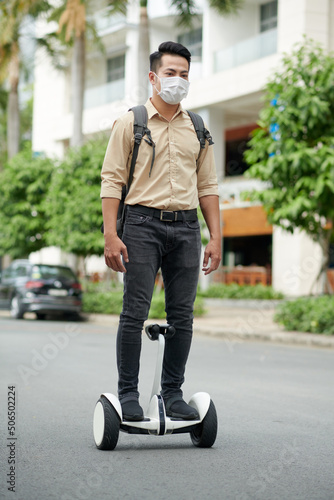Young man riding on two-wheeled personal transporter when hurrying to meeting in other office building © DragonImages