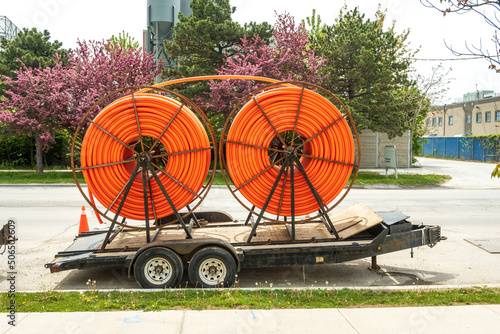 Canvas Print Large spools of smooth walled HDPE plastic cable (orange) conduit on trailers waiting to be installed and carry utility cables for new construction