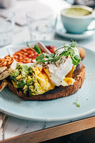 Healthy breakfast from poached eggs, grilled halloumi, Scrambled smoked harissa tofu, smashed avocado, grilled mushrooms and tomato beans on toast