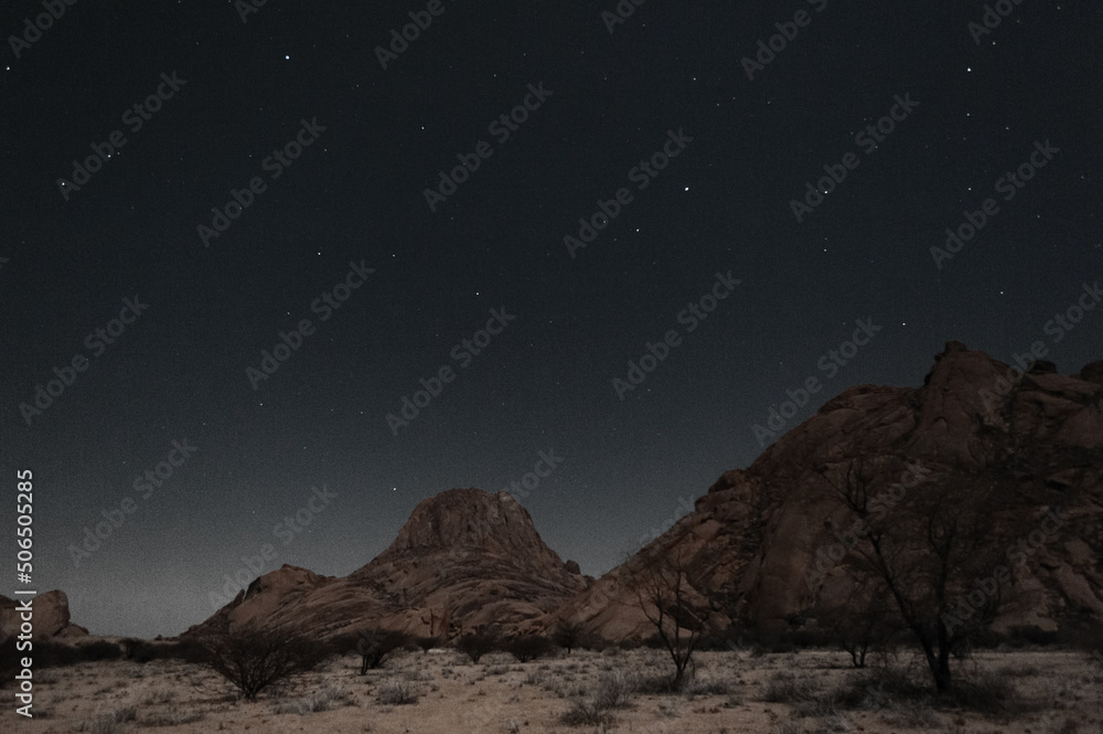 A starry night sky highlights the rocks of the namibian desert.