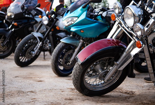 Photo of sports motorcycles displayed in a row. A row of motorcycle wheels with shiny metal