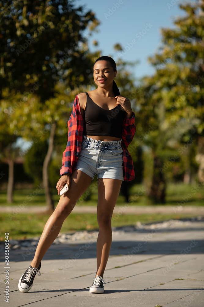 Beautiful young hot black woman in jeans shorts posing in hot summer sunshine. Beautiful young hot black woman in jeans shorts posing in hot summer sunshine.