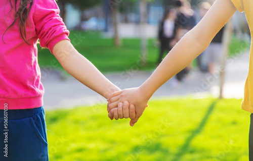Children walk together holding hands. Selective focus.