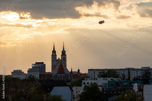 Zeppelin fliegt an der Johanniskirche in Magdeburg, Sachsen-Anhalt, Deutschland, im Sommer vorbei photo