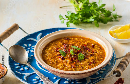 Red lentil and bulgur bride soup in a clay bowl on a light concrete background. Turkish cuisine. Recipes lentils, legumes