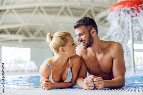 A lovely couple standing in the pool with thermal and mineral water and looking each other in the eyes. Romantic moments at spa and wellness center. Couple at the spa.