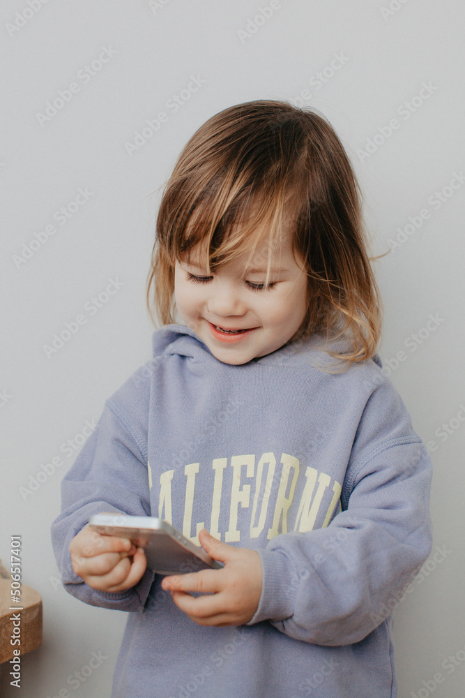 Little girl in violet hoodie using a phone on white background Little girl in violet hoodie using a phone on white background