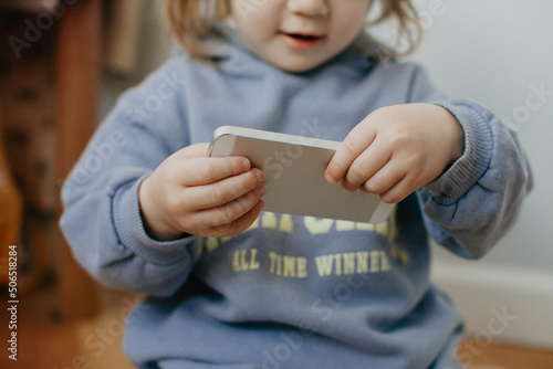 Little girl in violet hoodie using a phone on white background 