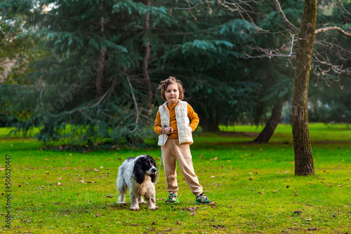 a little girl walks in the park with her pet, a Russian spaniel dog
