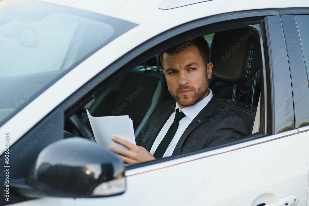 Always in a hurry. Handsome young man in full suit smiling while driving a car.