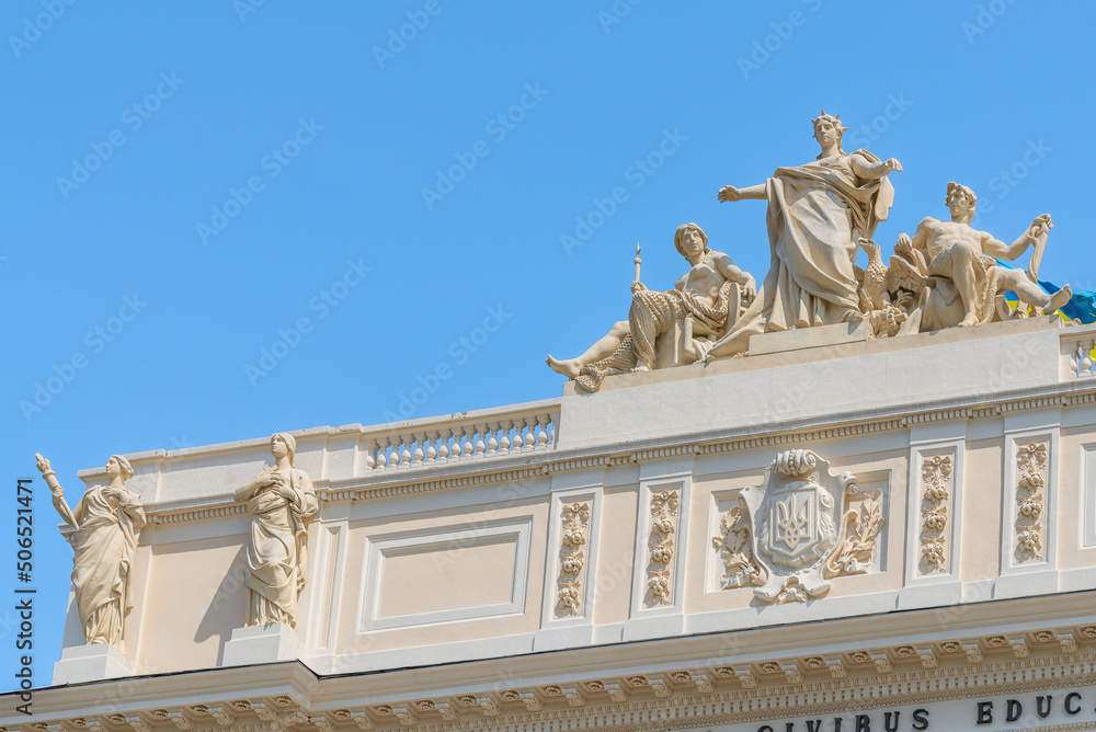 Lviv, Ukraine - May 2022: The upper part of Ivan Franko National University main building with National Flag of Ukraine. Allegorical sculpture composition Galicia, Vistula and Dniester. 