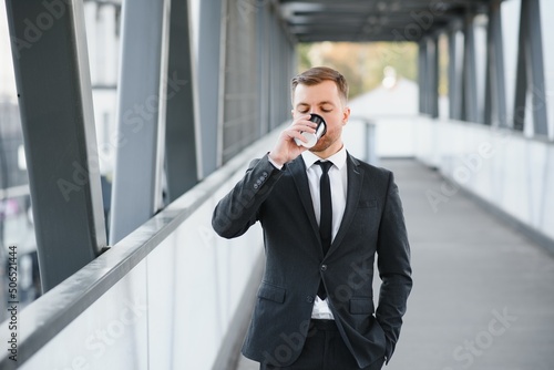 Takeaway coffee. Walk and enjoy fresh hot coffee. Waiting for someone in street. Man bearded hipster drink coffee paper cup. Businessman well groomed enjoy coffee break outdoors urban background