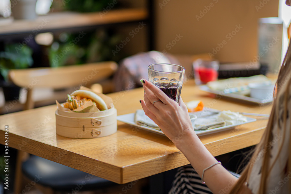 person in cafe with glass of drink