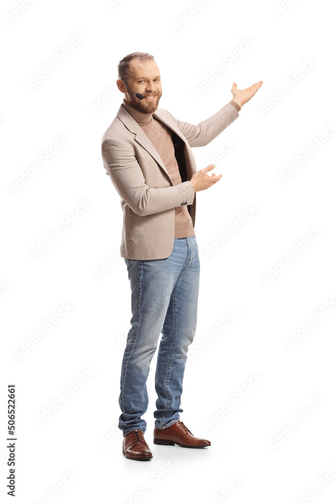 Full length shot of a young man with a headset presenting with hands Full length shot of a young man with a headset presenting with hands