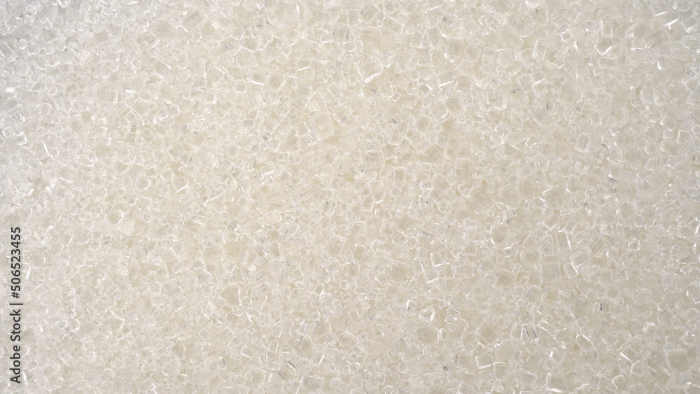 Sugar crystals fall on glass on a bright white background. Macro view of sugar. Sugar crystals fall on glass on a bright white background. Macro view of sugar.