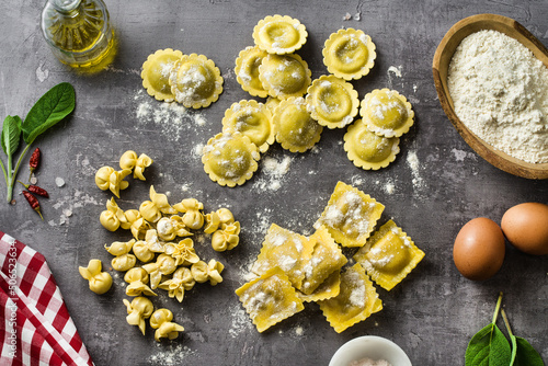 different types of fresh raw italian ravioli on the table with cooking ingredients. home kitchen