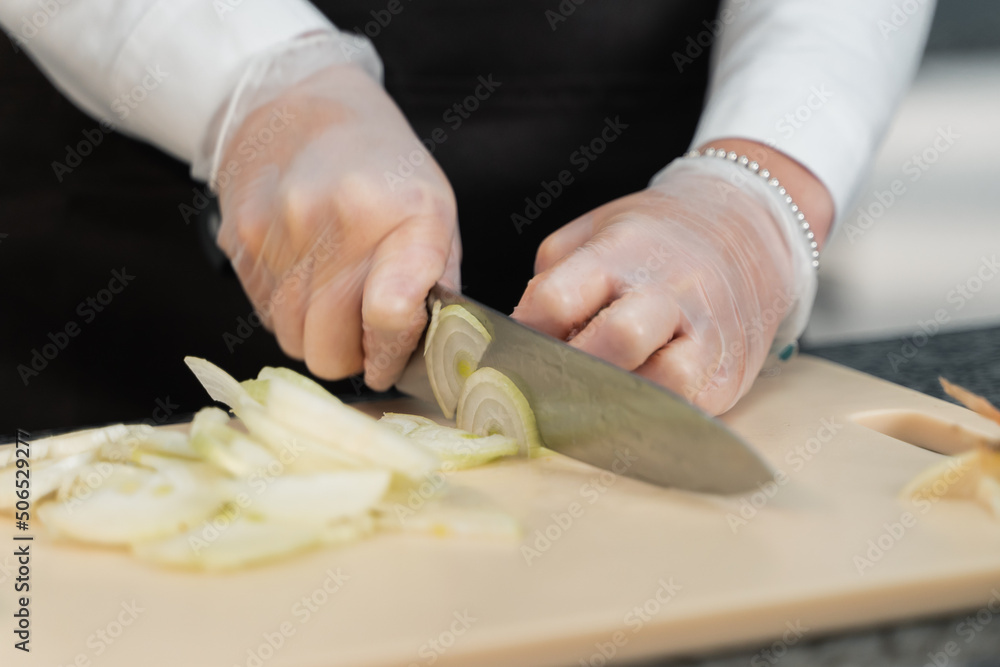 girl cuts onions with a knife in the kitchen