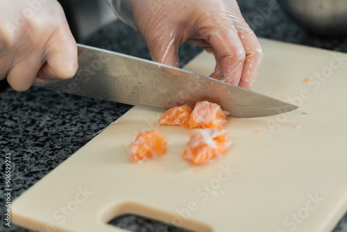 chef cuts salmon with a knife in the kitchen