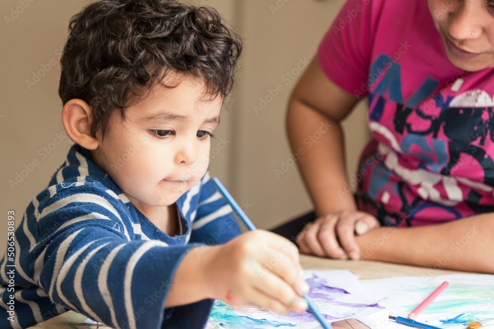 boy painting with his mom with brushes and paint boy painting with his mom with brushes and paint