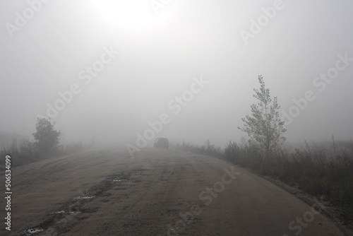 road travel with a car in heavy fog with precipitation in clouds