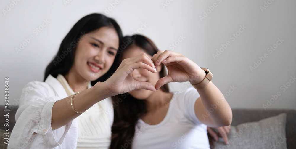 Happy LGBT lesbian couple holding hands in shape of heart. Happy LGBT lesbian couple holding hands in shape of heart.