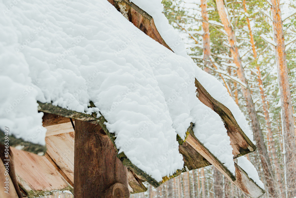Obraz premium Roof of wooden house is covered with snow. Sudden snowfall poured frost and ice. Cleaning shelter to preserve heat exchange. Hunter Forest Hut