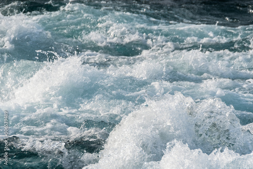 Bubbling ocean water at high tide. Turquoise sea waves foam, break into splashes.