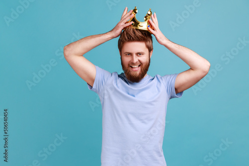 Bild auf Leinwand Portrait of happy bearded man wearing golden crown, imagining promotion at work to position, looking with arrogance, privileged status