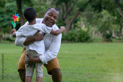 African father and son having fun in the park, father holding and raising his son, happy and cheerful