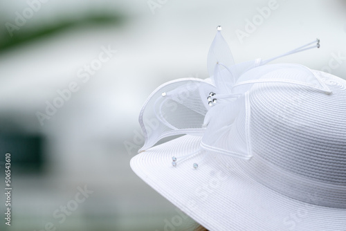 A lady wearing a white hat at a horse race.