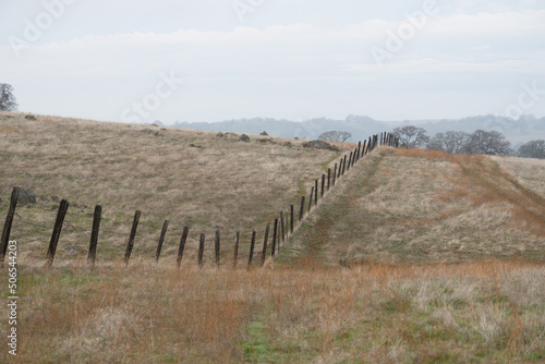 old wood post cattle fence over rolling hills