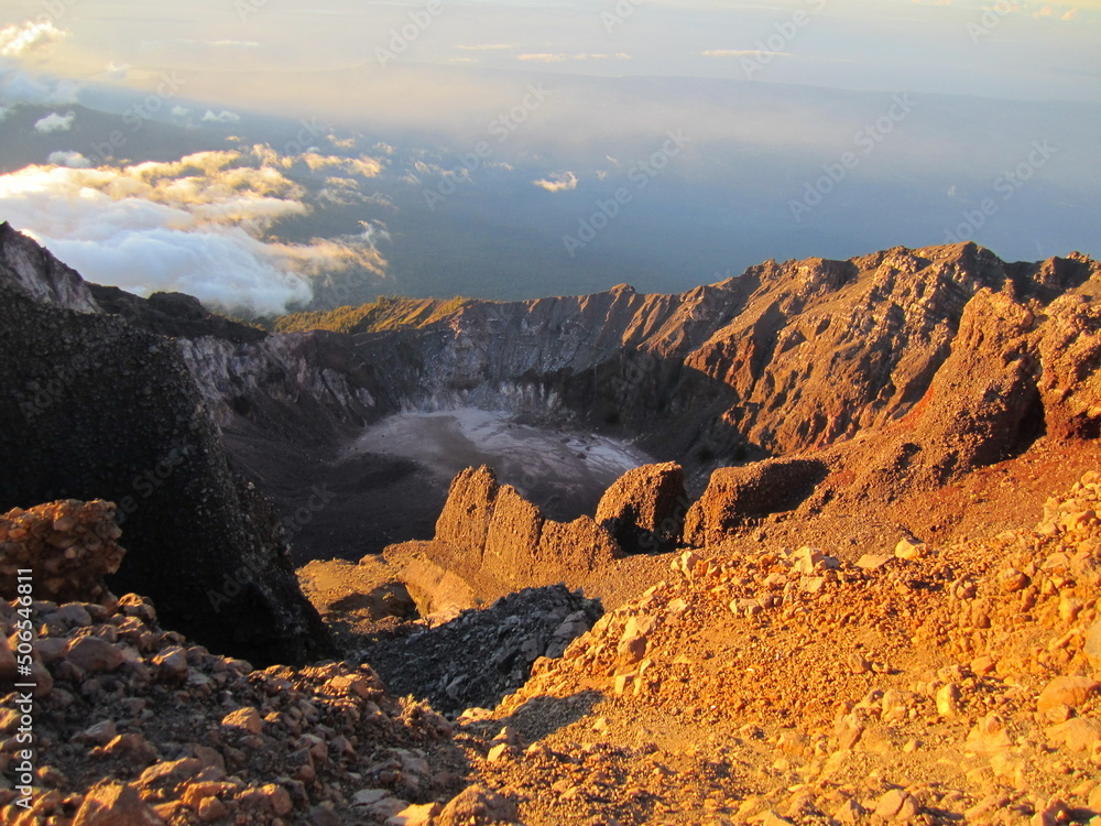 Sunrise at the top of Mount Rinjani in Lombok Island, Indonesia. View of crater lake covered in clouds from the summit. Beautiful sun rising in the horizon.