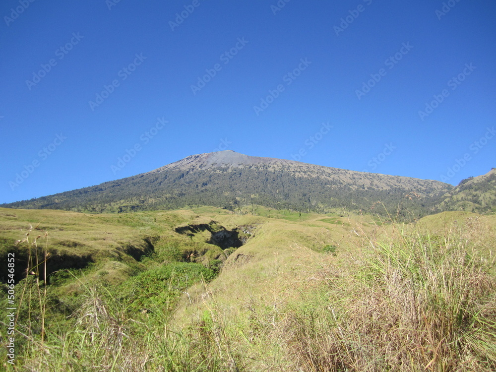 Mount Rinjani, the second highest volcano mountain in Indonesia, located in Lombok Island. A mountain with a beautiful crater lake called Segara Anak during a sunny day with blue sky.