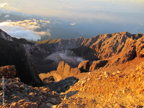 Sunrise at the top of Mount Rinjani in Lombok Island, Indonesia. View of crater lake covered in clouds from the summit. Beautiful sun rising in the horizon. © Diana