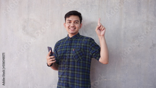 Young asian man with smiling expression pointing up photo