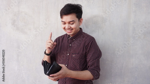 Young asian man in shirt smiling while holding wallet in hand photo