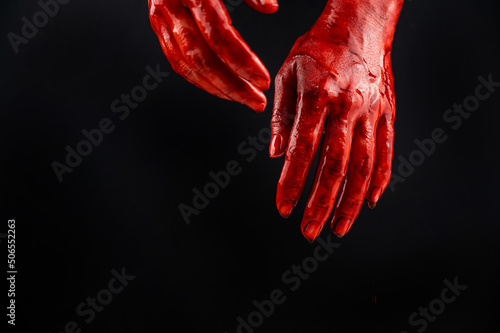 Women's hands in blood on a black background.