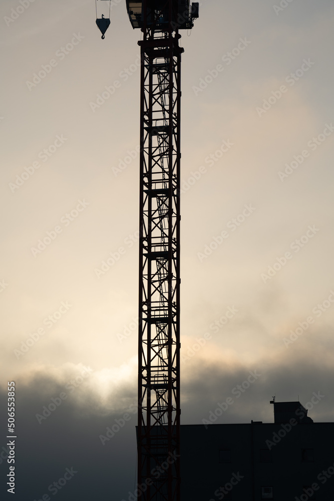 Construction crane in the evening with a cloudy sky in the background 
