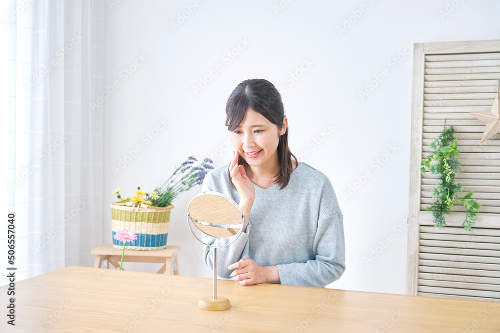 リビングで笑顔で卓上ミラーを見る女性 リビングで笑顔で卓上ミラーを見る女性