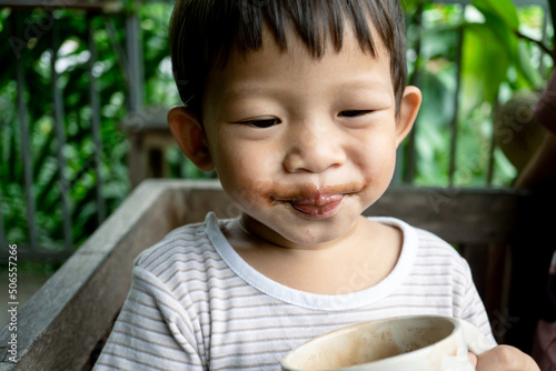 Smilng little boy with dirty chocolate on face.Asian boy.